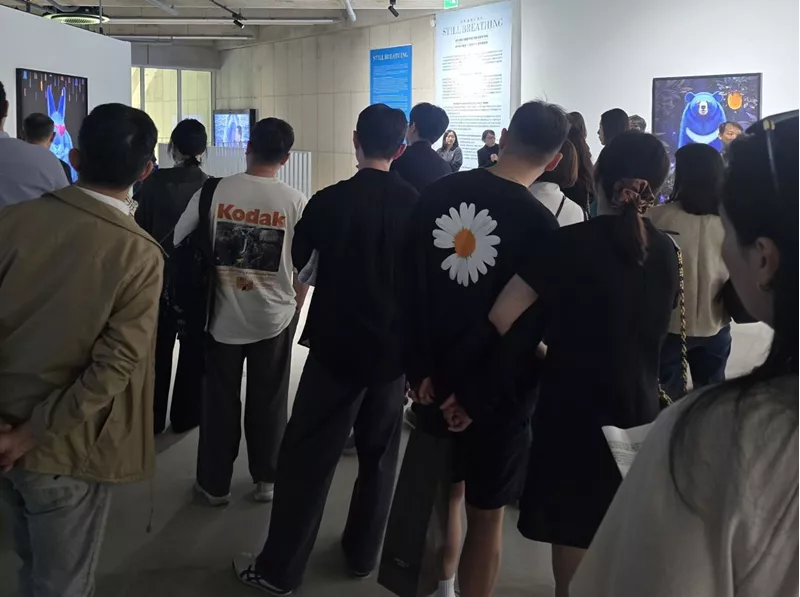고상우 작가의 개인전 오프닝 현장에서 작가의 설명을 듣고 있는 관객